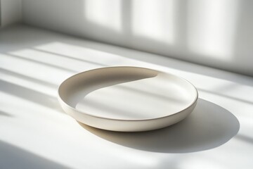 Leinwandbilder - A smooth ceramic plate is highlighted by linear shadows formed by window light, reflecting modern and minimalist design aesthetics, evoking a tranquil atmosphere.