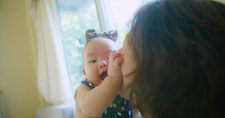 joyful mother holding smiling baby by window with greenery in background, mother and her baby enjoyi