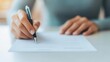 © ZpongXED - A hand holding a pen writes on a document, suggesting an act of signing, preparing, or creating written content.