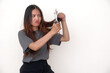 © Simon - Asian woman looking unhappy with her unhealthy hair, intending to cut it with scissors in her hand