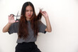 © Simon - Asian woman looking unhappy with her unhealthy hair, intending to cut it with scissors in her hand