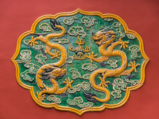 Intricate traditional palace Chinese wall decoration featuring two golden dragons on a red background, symbolizing power and luck in Asian culture