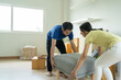 © Pormezz - Asian couple moving heavy furniture to new home.