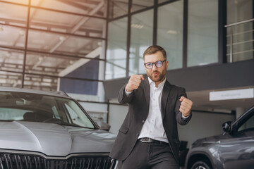 Wall Mural - Yes, that's my new car! Customer in car dealership. Happy bearded man new car owner shows driving a car