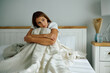 © Drazen - Young pensive woman sitting on bed in morning.