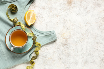 Wall Mural - Cup of diet tea, measuring tape, lemon and stylish sports top on light background. Weight loss concept