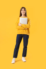 Canvas Print - Young woman with laptop on yellow background