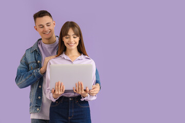 Canvas Print - Young couple using laptop on lilac background