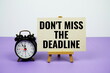 © may1985 - Don't miss the deadline text on paper card with alarm clock on purple background