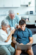 © simona - Elderly grandparents engage with their grandson as he shares insights into web navigation and digital tools, helping them learn new skills and connect with the internet on a laptop