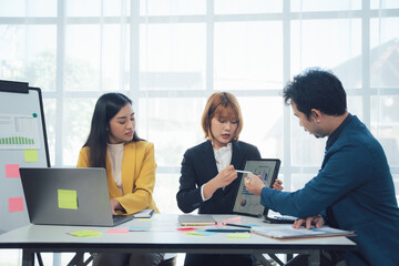 Teamwork Makes the Dream Work: Collaborative business meeting. Three colleagues engage in a productive discussion, analyzing data on a tablet.  Modern office setting. 