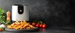 © Being Imaginative - An air fryer next to crispy fries on a countertop, dark backdrop with lots of copy space