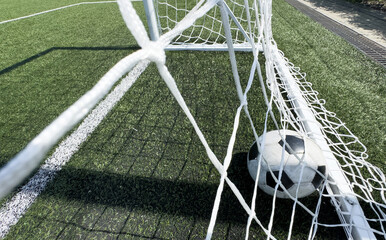 Wall Mural - Soccer ball on artificial bright and dark green grass at public outdoor football stadium