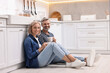 © New Africa - Happy middle aged couple with cups of drink on floor in kitchen