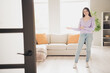 © deagreez - Full size photo of attractive young teen woman hands point welcome dressed purple outfit bright cozy day light home interior living room