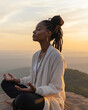 © axel - A Black woman sits peacefully on a mountain peak, meditating with closed eyes as the sun rises, surrounded by breathtaking natural beauty and tranquility