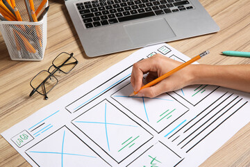Wall Mural - developing ui design. designer with smartphone creating website wireframe on paper at wooden table, 