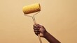 © RaptorWoman - Close-up of a hand gripping a paint roller against a plain beige background, symbolizing painting and home improvement.