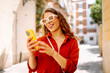 © maxbelchenko - Beautiful woman using phone walking in city street. Lifestyle, travel, tourism, technology, blogging, communication concept.