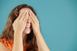 © Lucia PSV - Young pretty woman isolated over blue background. Hiding her eyes with her hands while smiling. Shyness. Embarrassment. Introversion, fear. She is going to get a surprise that will make her very happy