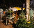 Wooden Christmas market booth decorated with evergreen trees and festive ornaments, captured under warm lights in an evening street scene