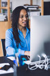 © BullRun - Young African American woman speaking at work place using earphones and computer