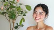 © chic designs - 白い背景にピンクの花が咲いた緑の植物のそばで微笑む喜びに満ちた女性