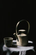 © Joske - A ceramic tea set catching light in a moody setting.