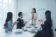 © Kritdanai - Successful Presentation: Applause and appreciation fill the modern office as a female executive delivers a winning presentation to her diverse team.