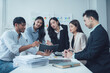 © Wicitr - Teamwork Makes the Dream Work: A diverse group of business professionals collaborates around a table, engaged in a serious discussion over documents and charts.