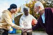 © Marko Geber - Senior men playing basketball outdoors team huddle