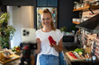 © Geber86 - Young woman filming cooking tutorial in kitchen with fresh vegetables and eggs