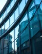 © ntpscl - Intricate details of a modern architecture with a curved design, showcasing layered glass panels in varying shades of blue the reflection