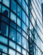 © ntpscl - Intricate details of a modern architecture with a curved design, showcasing layered glass panels in varying shades of blue the reflection