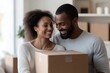 © Milos - A joyful couple is smiling together while holding a cardboard box, embodying themes of partnership, new beginnings, and the excitement of moving into a new space.