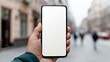 © alex - Hand holding phone with blanc white screen mockup against a blurry background. AI generated