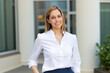 © Minerva Studio - Smiling businesswoman standing outside office building
