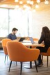© Mandeep - Cozy workspace with comfortable orange chairs and people working on laptops