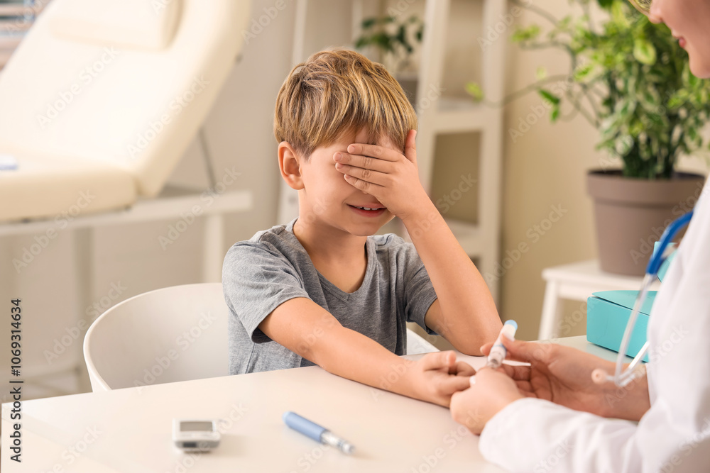 Scared little diabetic boy with doctor using lancet pen at table in clinic