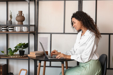 Sticker - Young African-American author using laptop at table in cafe