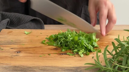 Canvas Print - cook housekeeper chopping parsley on wooden cutting board in kitchen. process of making homemade meal, cooking at home, food closeup