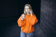 © ADDICTIVE STOCK - Woman in Cozy Knitted Orange Sweater Holding Coffee Cup