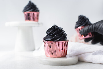 Sticker - Black frosting on Pink cupcakes with a white background, cupcakes in pink foil liners with black buttercream