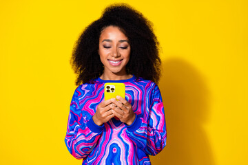 Photo portrait of attractive young woman hold telephone dressed stylish colorful blue clothes isolated on yellow color background