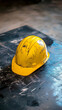 © thien - worn yellow hard hat rests on messy black surface, symbolizing construction work and safety. Its weathered appearance reflects hard labor of job