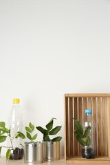 Poster - Recycling concept. Metal cans and plastic bottles with plants on wooden table, space for text