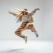 © Surachetsh - Young woman in  fashionable, light toned hip hop and performance dance outfit performs high energy dance move against white studio background, radiating confidence and strength.