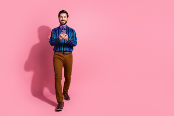 Wall Mural - Photo of cheerful groomed nice elegant man wear stylish clothes walk empty space isolated on pink color background