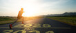 © Yingyaipumi - New year 2025 or start straight concept.word 2025 written on the asphalt road and athlete woman runner stretching leg preparing for new year at sunset.Concept of challenge or career path and change.