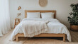 © Nordic - A wooden bed frame with white linen bedding and a woven throw blanket at the foot
